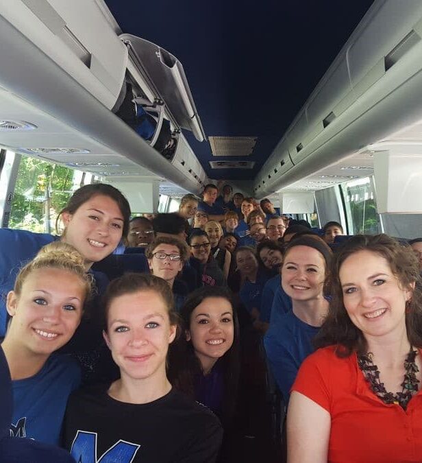 smiling students traveling on coach bus